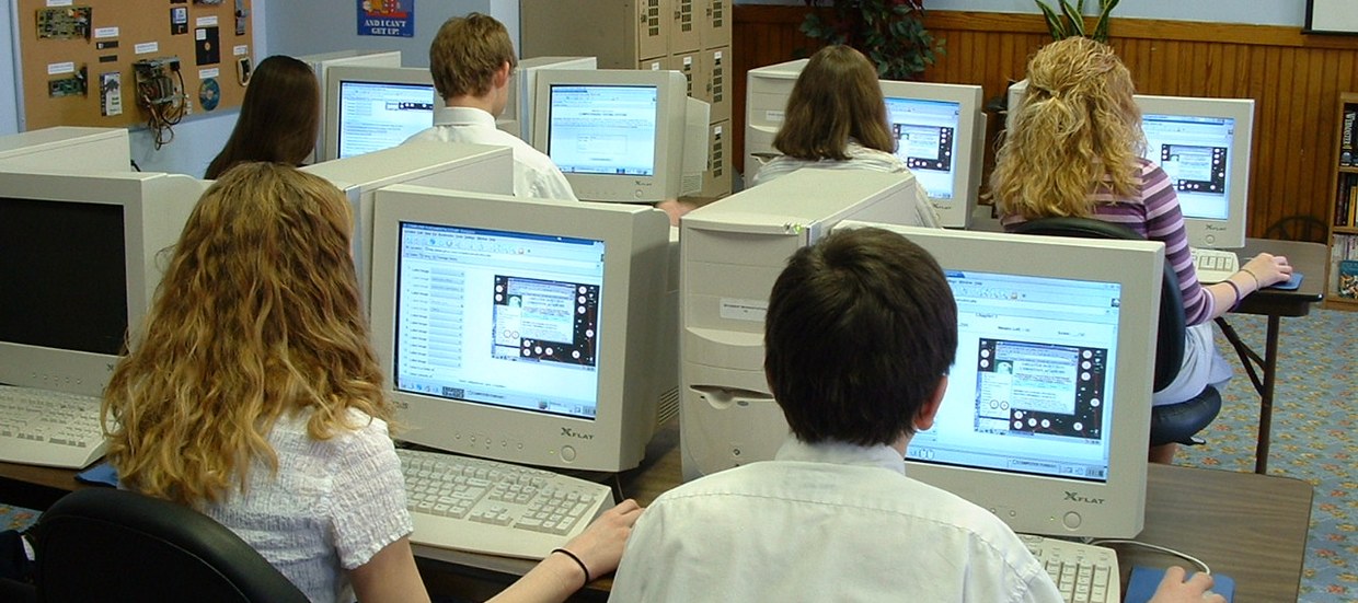 A row of students at boxy CRT computers taking a test in a classroom, some time in the mid 2000s
