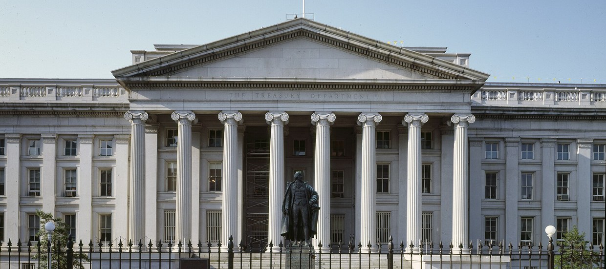 The columned front of the United States Treasury building in Washington, with the Hamilton statue in front of it