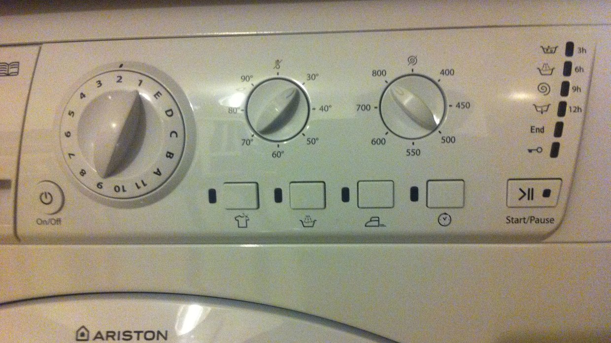 Control panel of an Ariston washing machine with a twelve-position programme dial, a temperature dial marked 30 to 90 degrees, a spin speed dial marked 400 to 800, and a row of unlabelled icon buttons